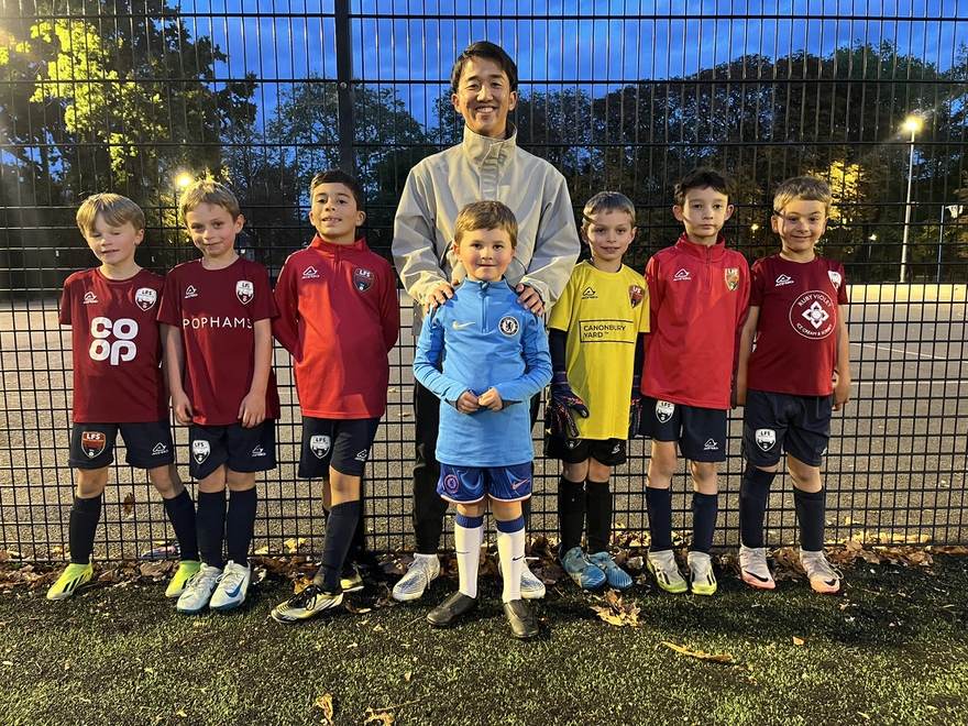 ロンドンのグラウンドで、ユニフォーム姿の子どもたちとコーチ
